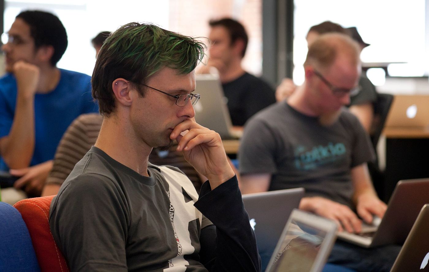 A programmer reviewing lines of code on a large monitor in a dim office.