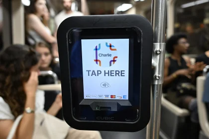 A contactless fare reader on a train invites passengers to tap here and pay, the everyday face of digital payments.